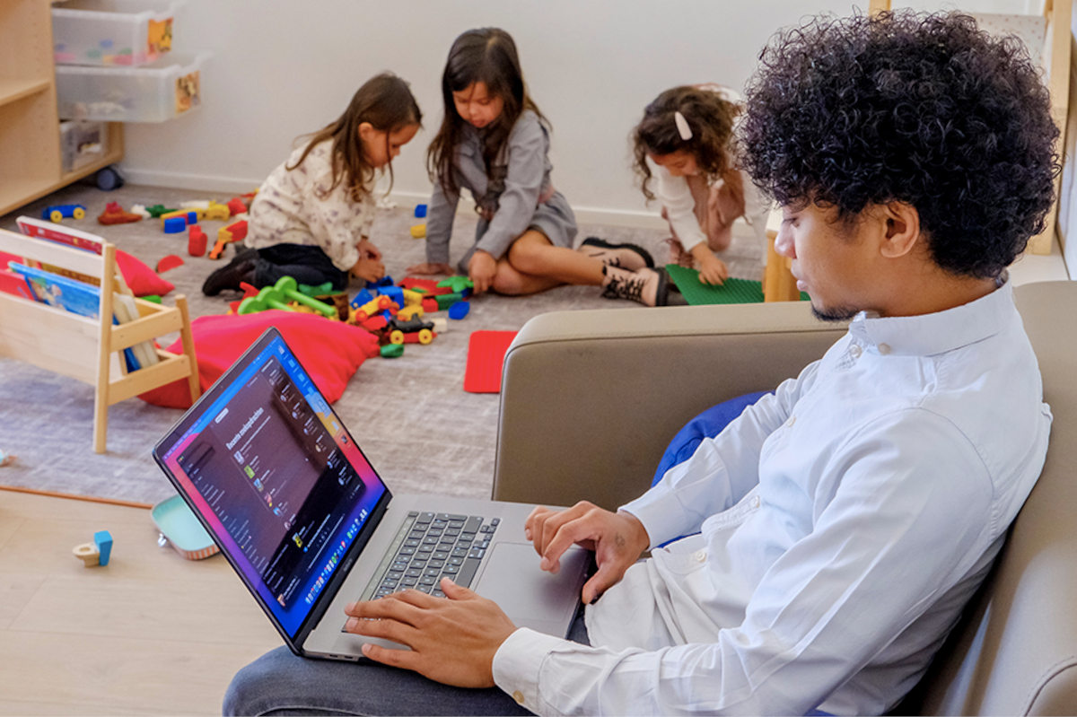 Kind met laptop, met spelende kinderen op de achtergrond media ukkie dagen