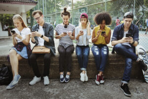 afbeelding van zes jongeren op hun smartphone bij artikel over fear of missing out