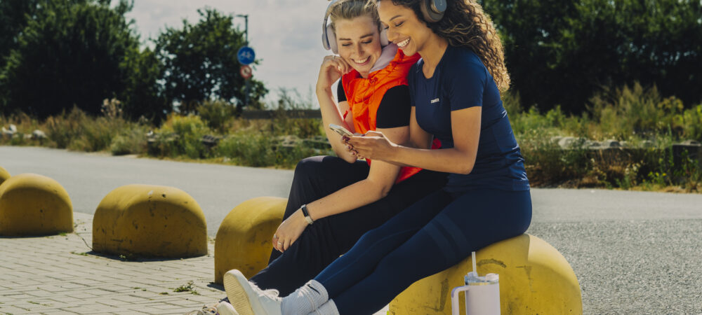 Twee vrouwen in hardloopkleding kijken naar een telefoon