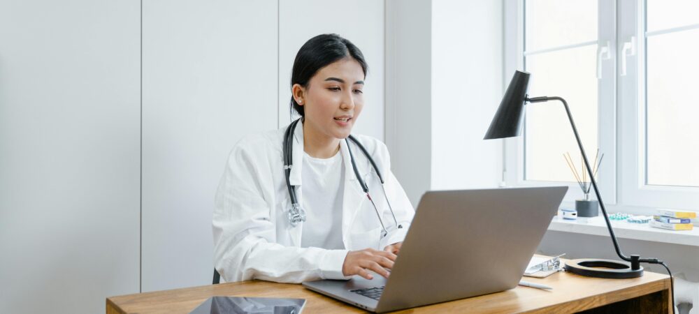 Een dokter zit achter een laptop