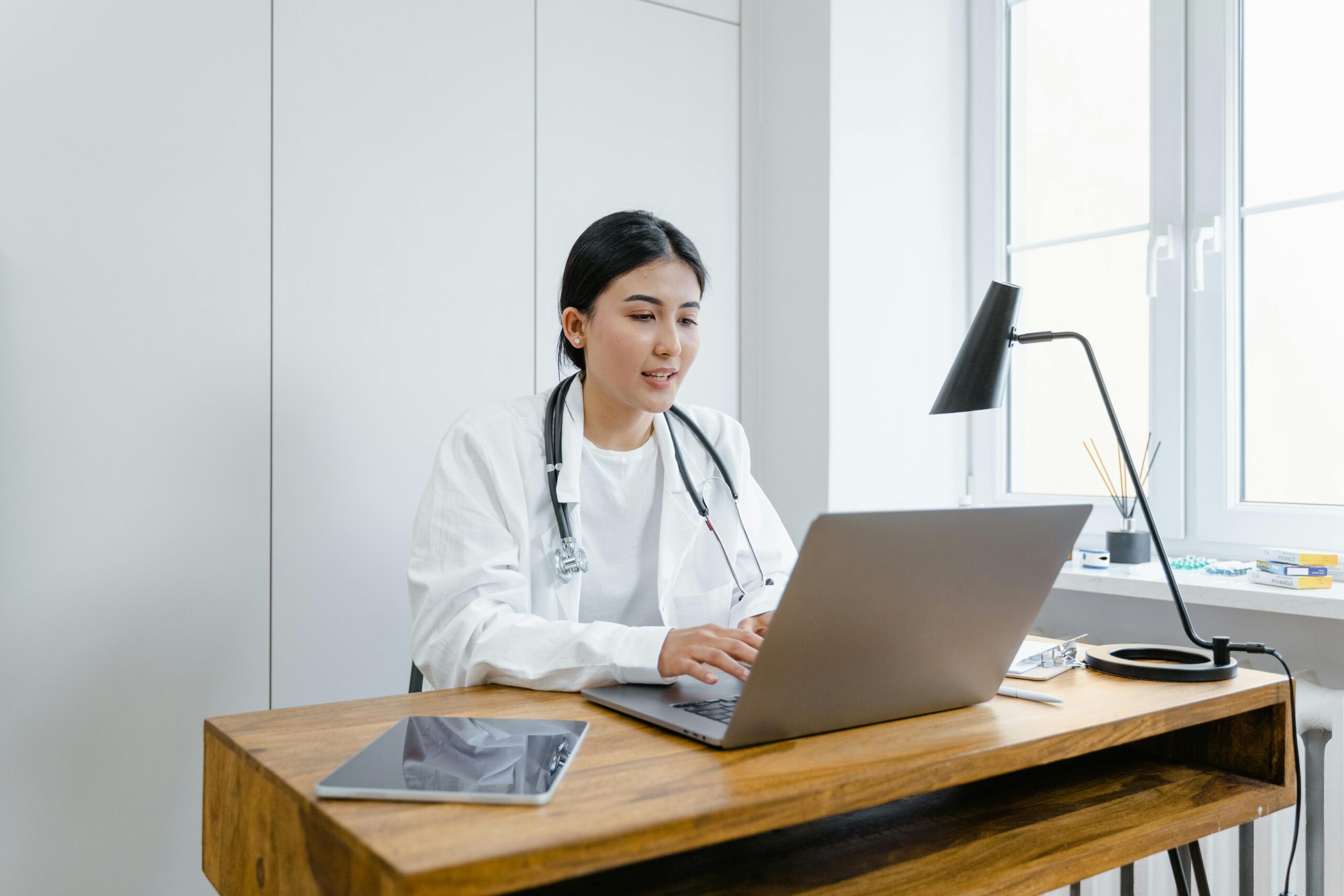 Een dokter zit achter een laptop